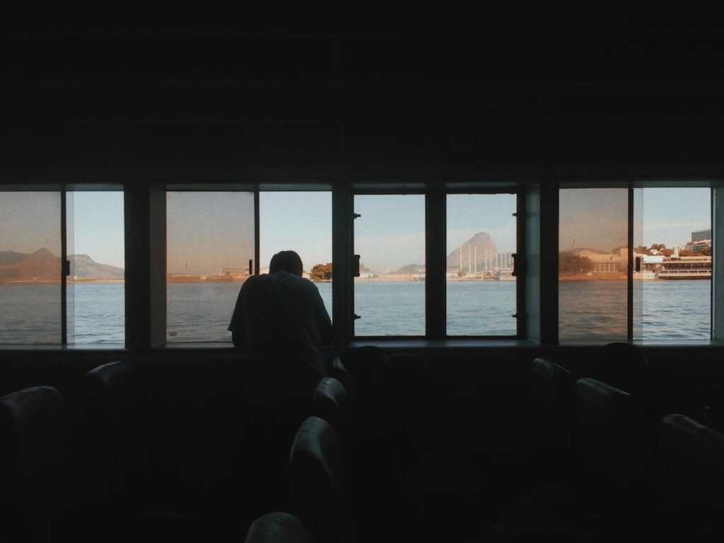 Silhouette of Man Sitting on Chair Near Body of Water